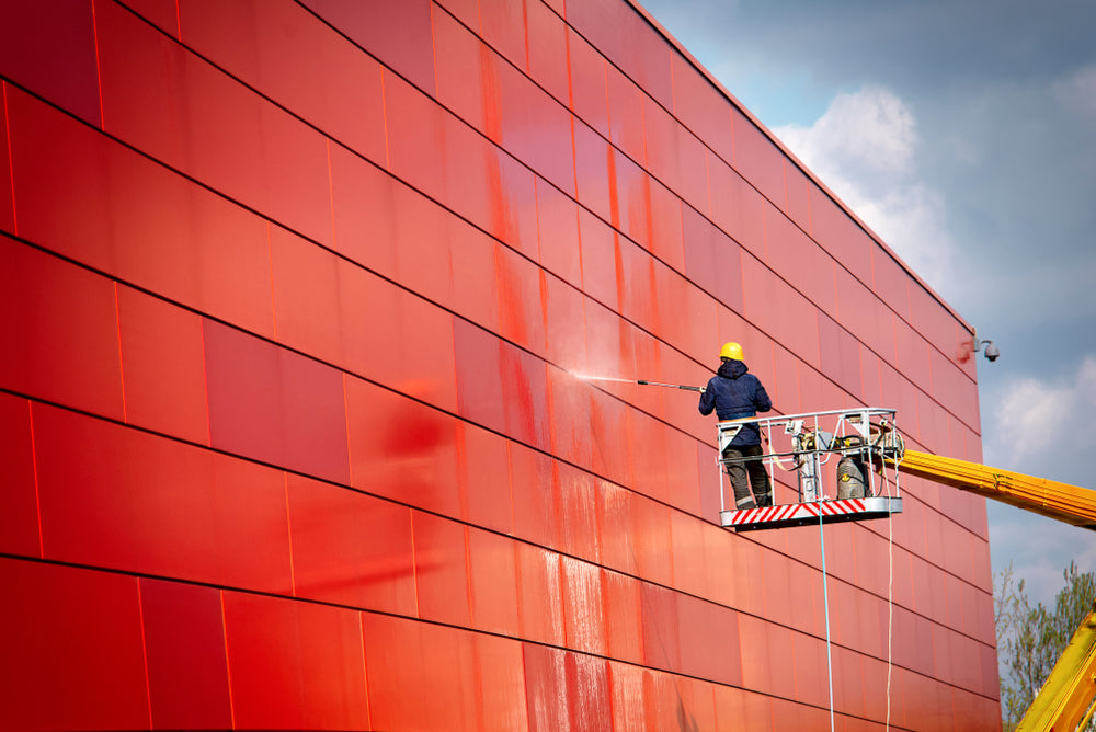 Cleaning a building's red facade for Net Zero training.