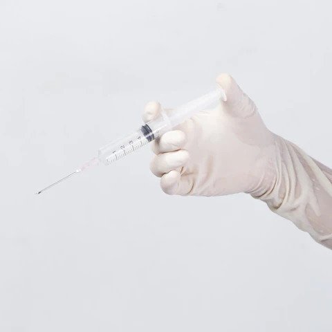 Medication assist syringe held by gloved hand.