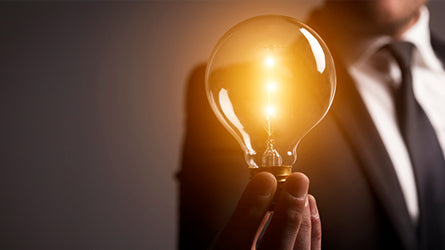 Man holding glowing light bulb, encouraging innovation