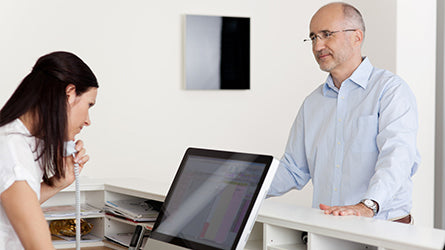Man at reception desk with staff.